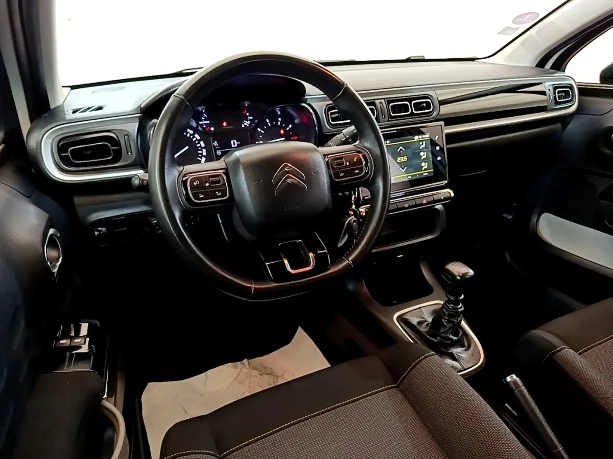 Intérieur noir de Citroën C3 2021, vue du poste de conduite avec volant cuir multifonctions et écran tactile central.