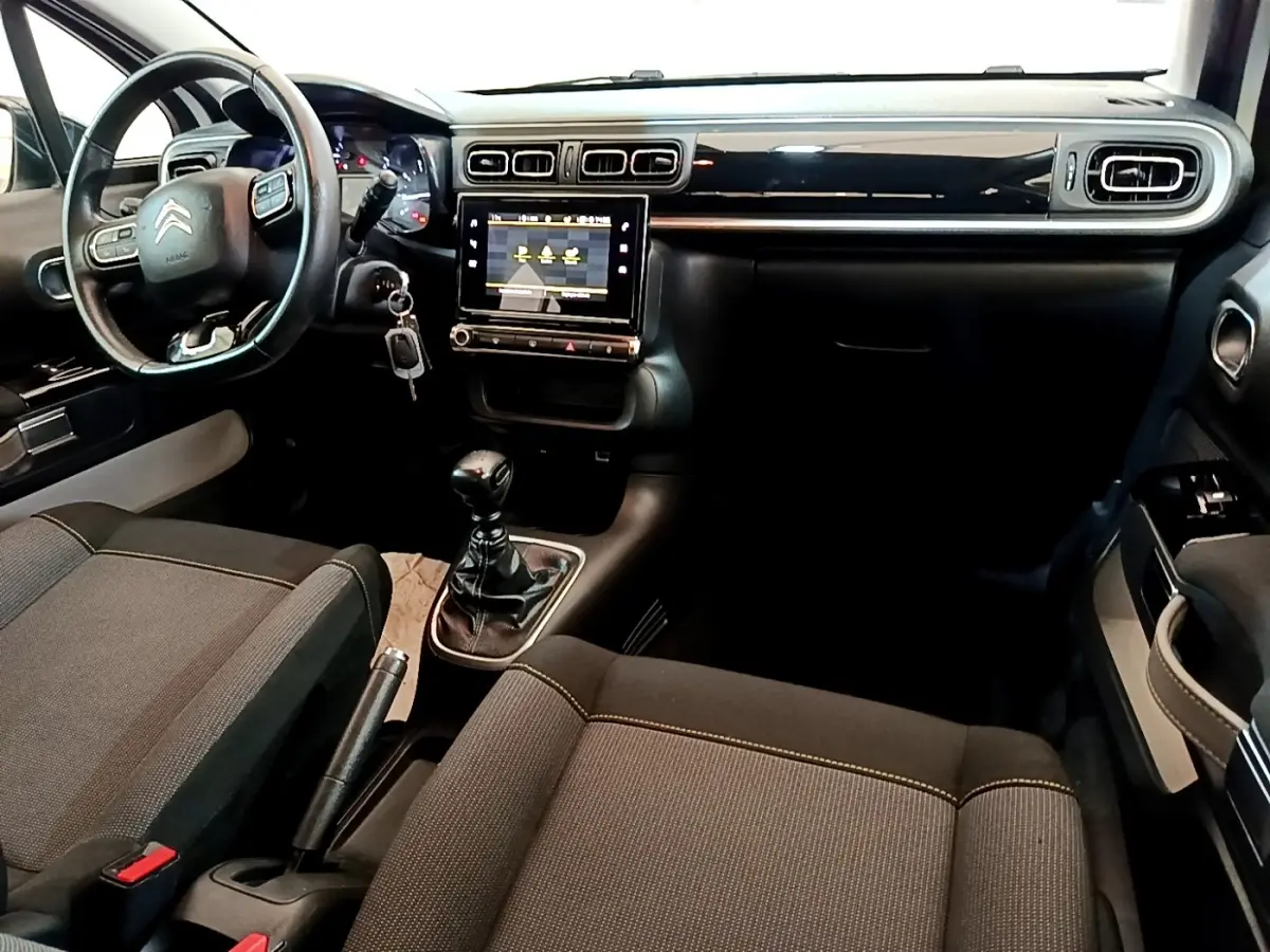 Vue intérieure avant droite du Citroën C3 blanc, montrant le volant cuir multifonctions et l’écran tactile central.