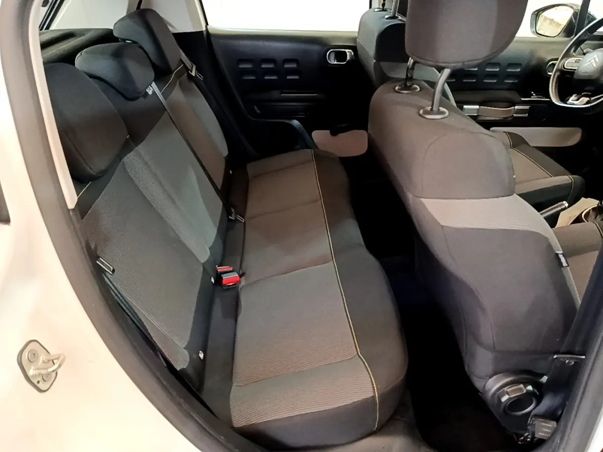 Vue intérieure côté gauche montrant la banquette arrière noire et grise de la Citroën C3 blanche 2021.
