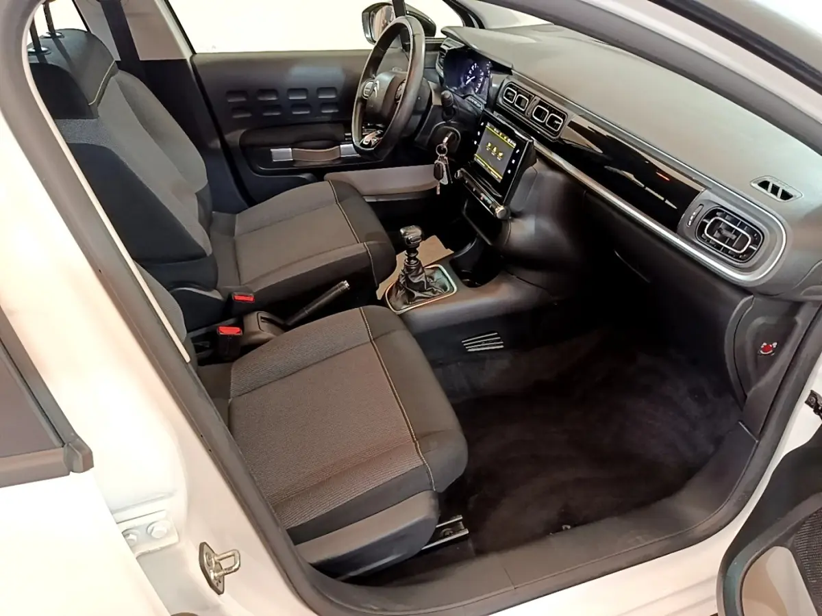 Vue intérieure côté conducteur de la Citroën C3 blanche 2021, volant cuir multifonctions et écran tactile central.