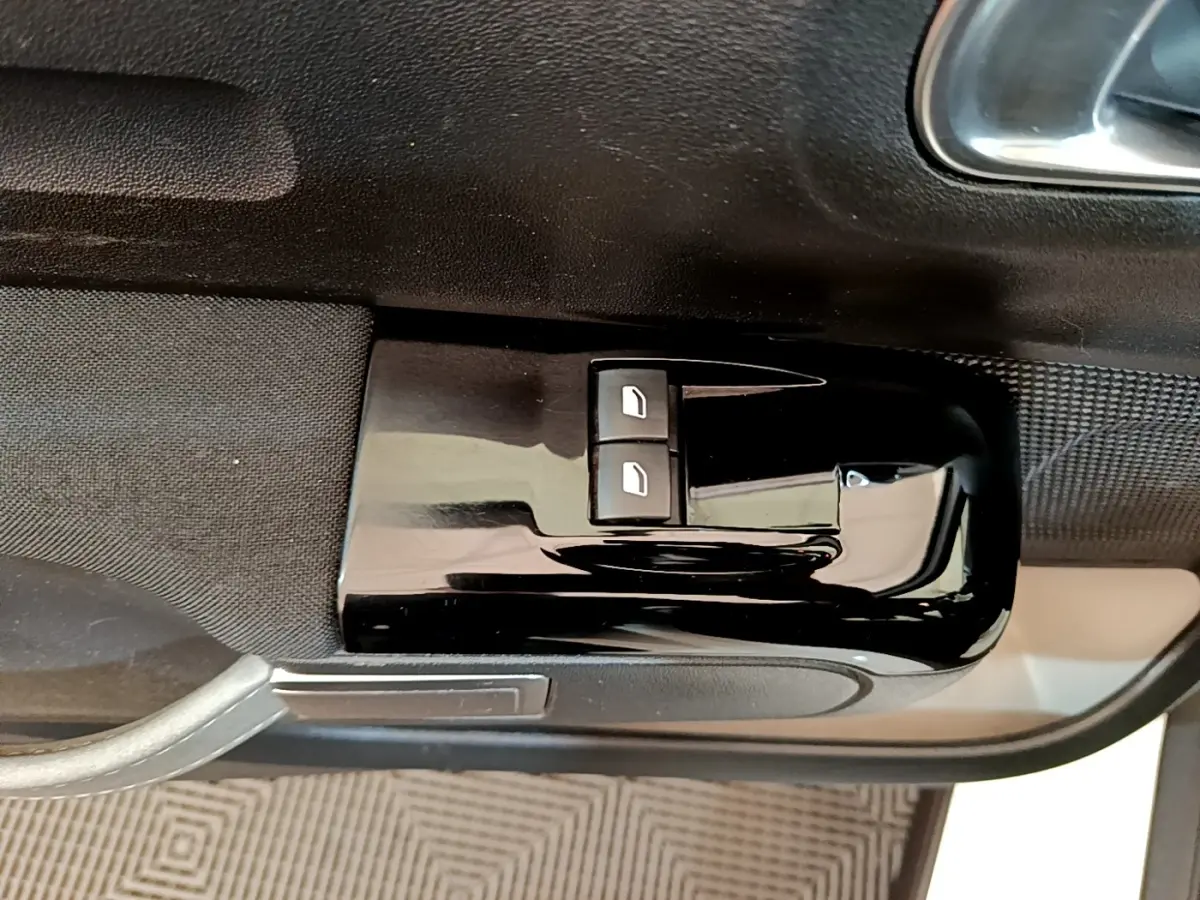 Gros plan sur les commandes de lève-vitres électriques côté conducteur d'une Citroën C3 blanche de 2021.