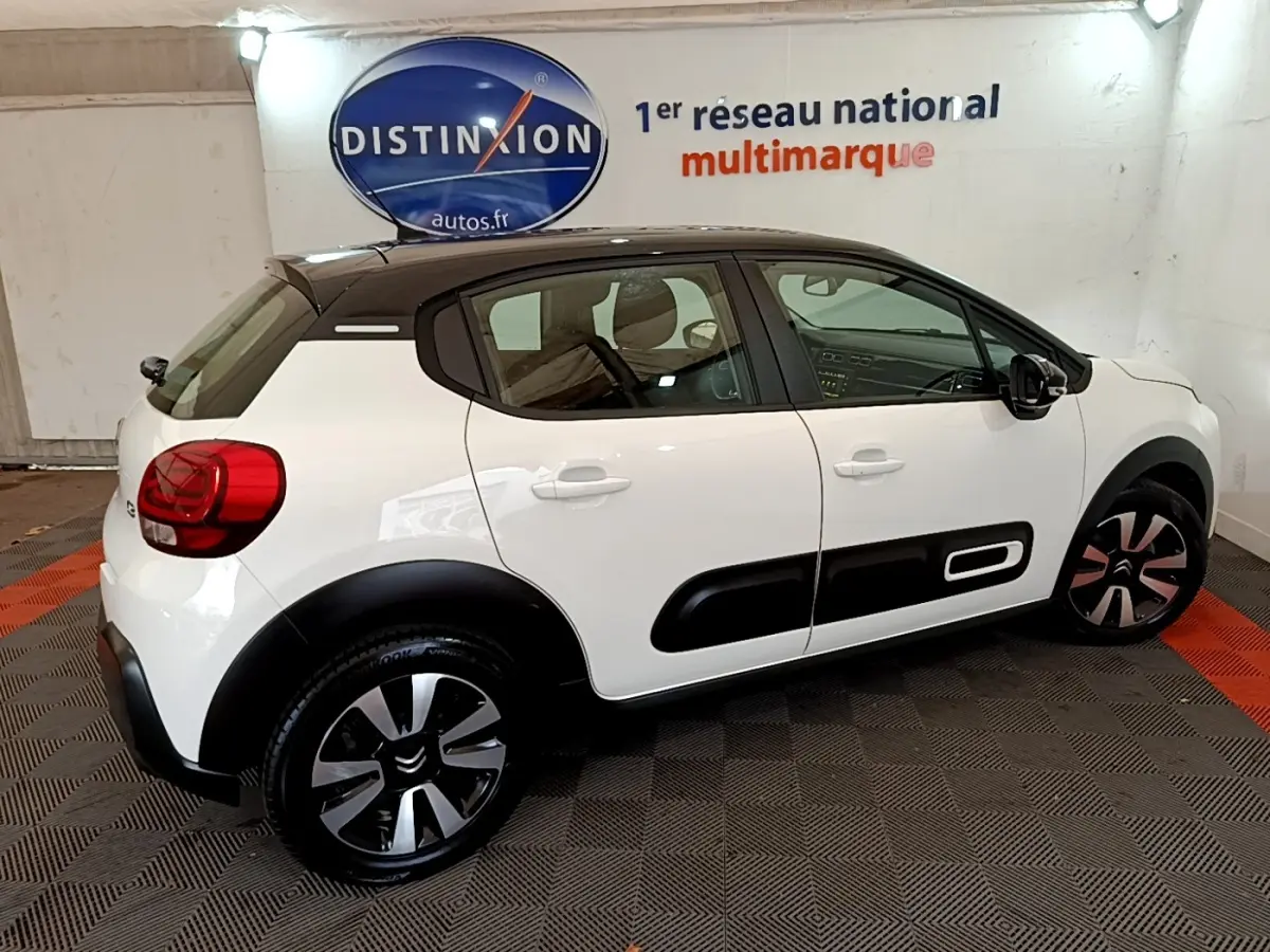 Citroën C3 blanc vue de profil droit, toit noir, avec protections latérales noires et jantes stylisées.