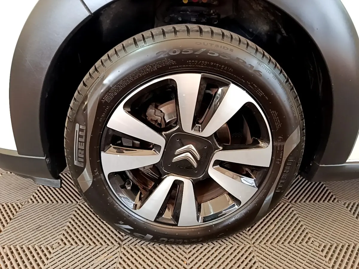 Gros plan sur la roue avant gauche avec jante alliage bicolore et logo Citroën sur une Citroën C3 blanche.