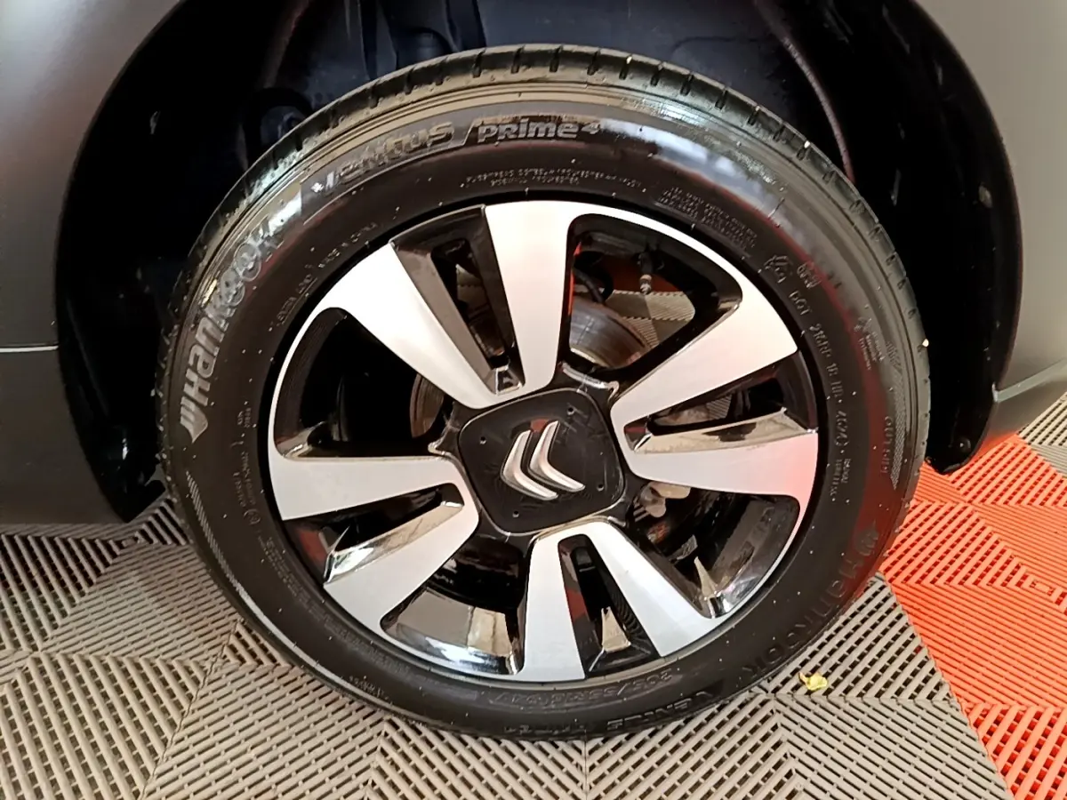 Gros plan sur la jante avant droite noire et argentée avec logo Citroën, sur roue de Citroën C3 blanche.