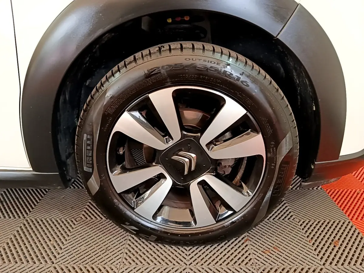 Gros plan sur la roue avant droite d'une Citroën C3 blanche, mettant en valeur la jante noire et argentée au logo Citroën.