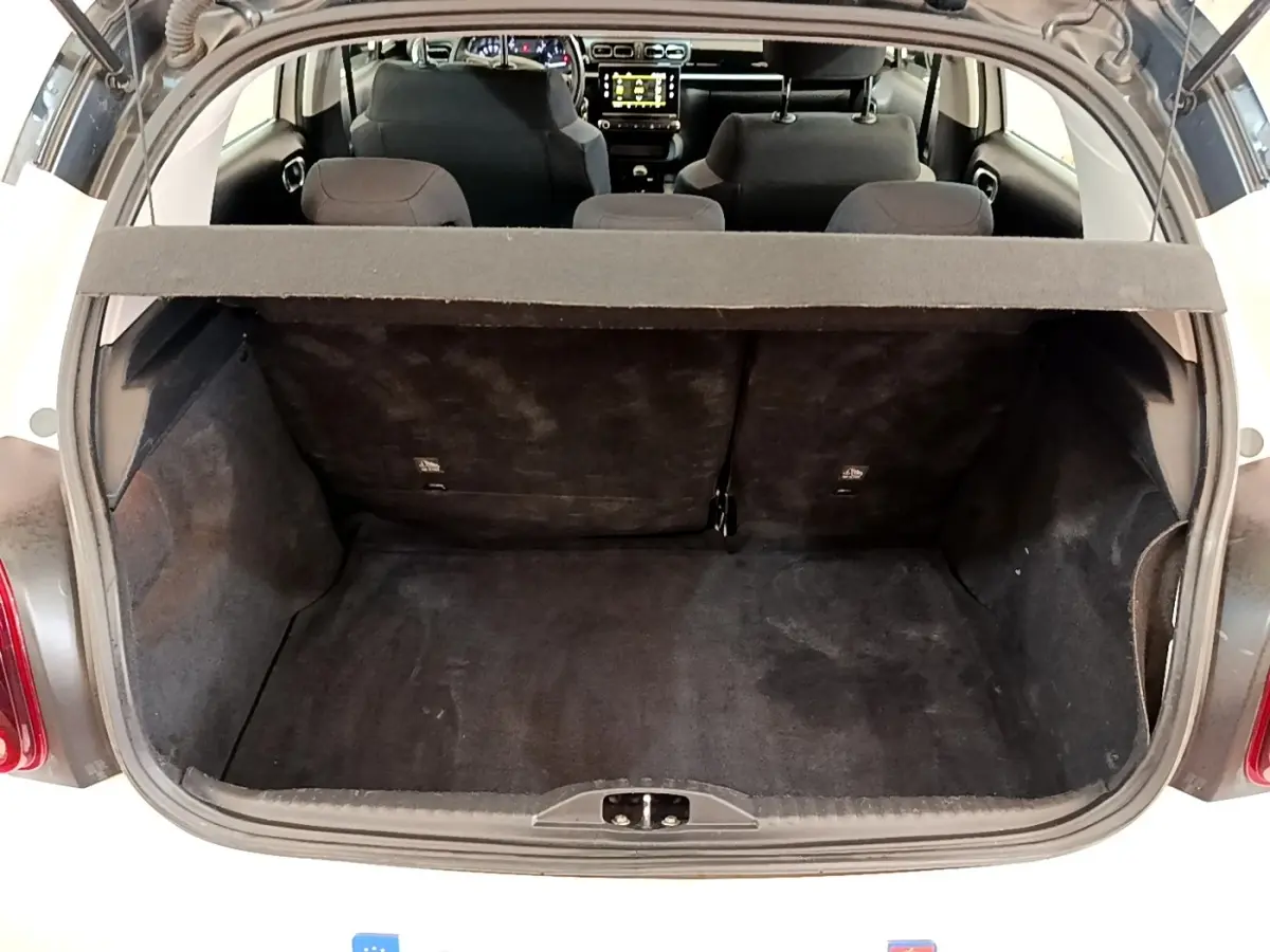 Vue arrière du coffre ouvert d'une Citroën C3 blanche, montrant l'espace de chargement et les sièges arrière.