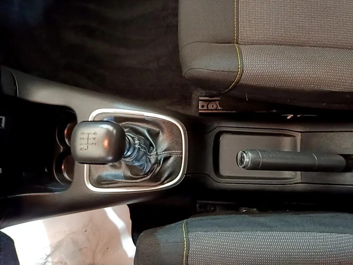 Vue plongeante sur la console centrale de la Citroën C3 blanche, avec levier de vitesse manuel et frein à main entre les sièges.