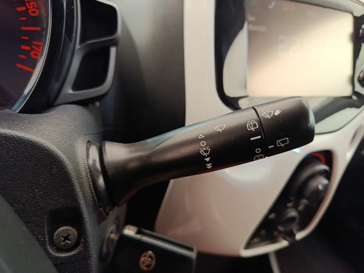 Gros plan sur la commande d’essuie-glaces à gauche du volant dans l’habitacle blanc d’une Toyota Aygo 2016.