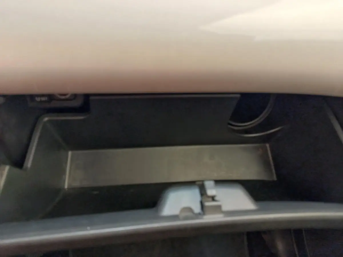 Intérieur du coffre à gants noir de la Toyota Aygo blanche, vue rapprochée sans objets visibles.