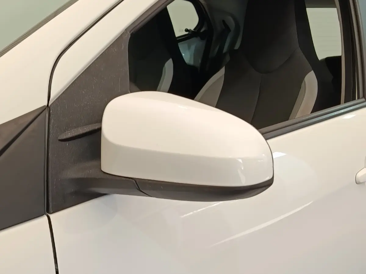 Gros plan sur le rétroviseur extérieur gauche blanc d'une Toyota Aygo 2016, avec siège conducteur visible en arrière-plan.