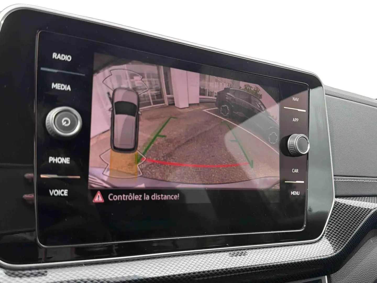 Écran tactile intérieur montrant la caméra de recul avec indications visuelles du Volkswagen T-Cross gris.