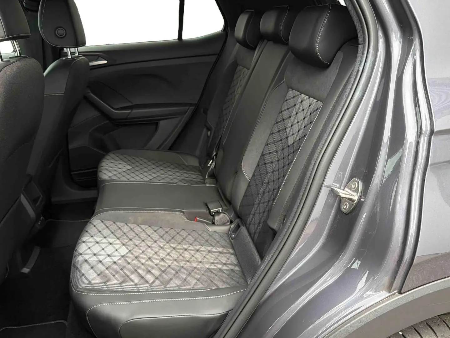 Vue intérieure côté droit sur les sièges arrière gris à motifs du Volkswagen T-Cross 2025 avec porte ouverte.