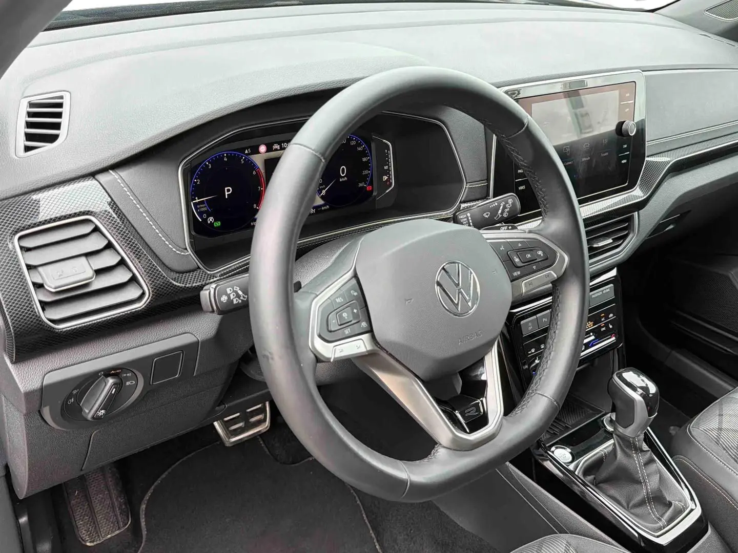 Vue intérieure du volant cuir et tableau de bord digital du Volkswagen T-Cross 2025 avec boîte manuelle, finition gris et détails noirs.