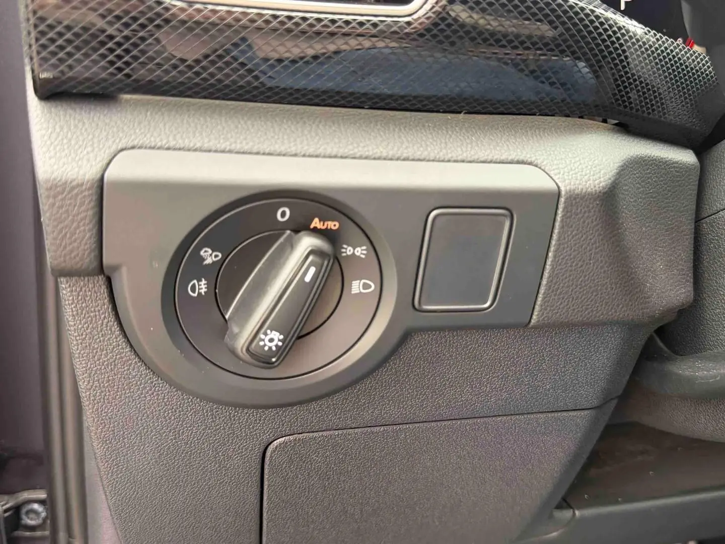 Gros plan sur le bouton de commande des phares avec réglage automatique dans l’habitacle du Volkswagen T-Cross gris.