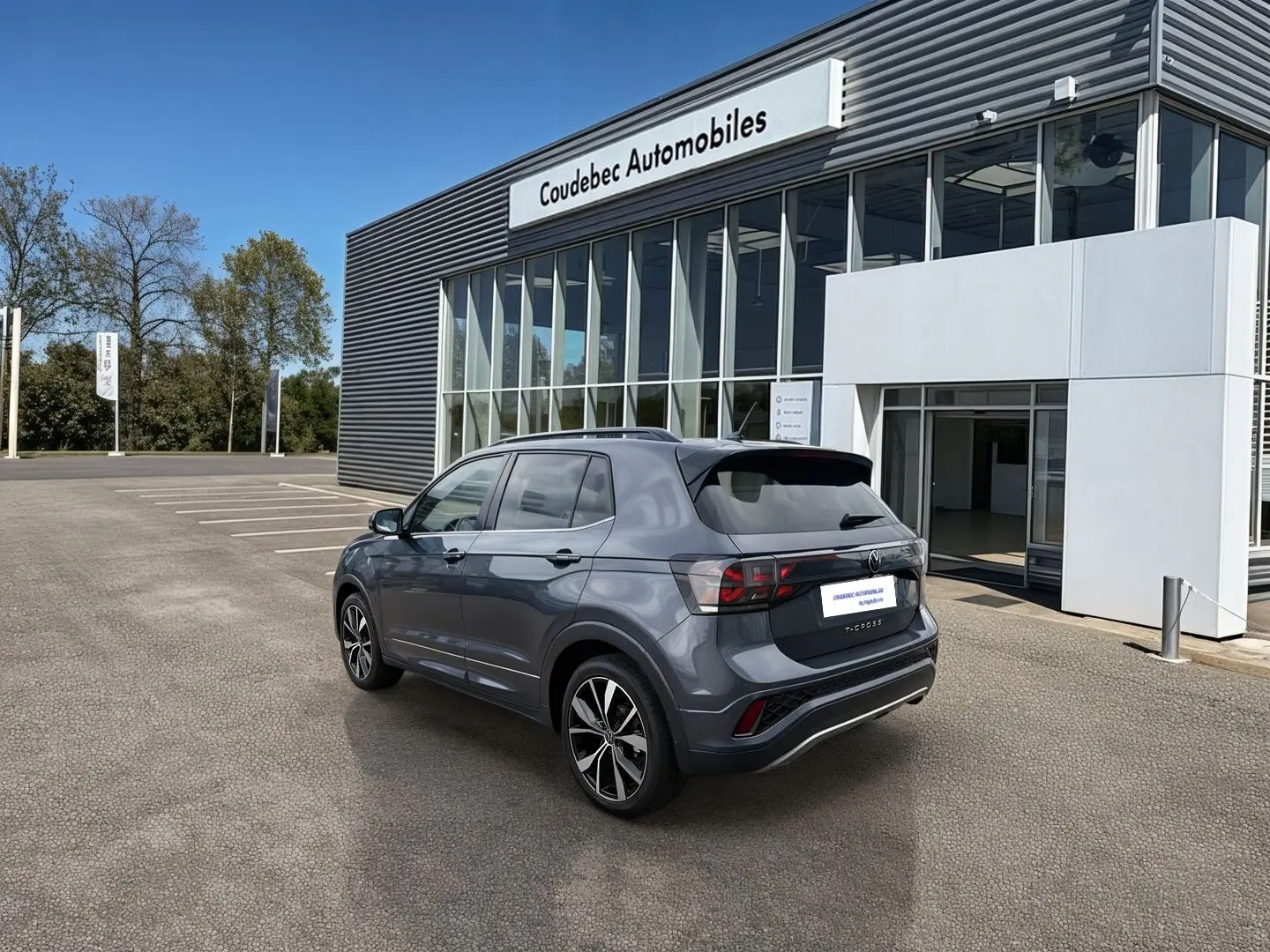 Volkswagen T-Cross gris vue 3/4 arrière droit, jantes alliage 18 pouces, stationné devant un concessionnaire.