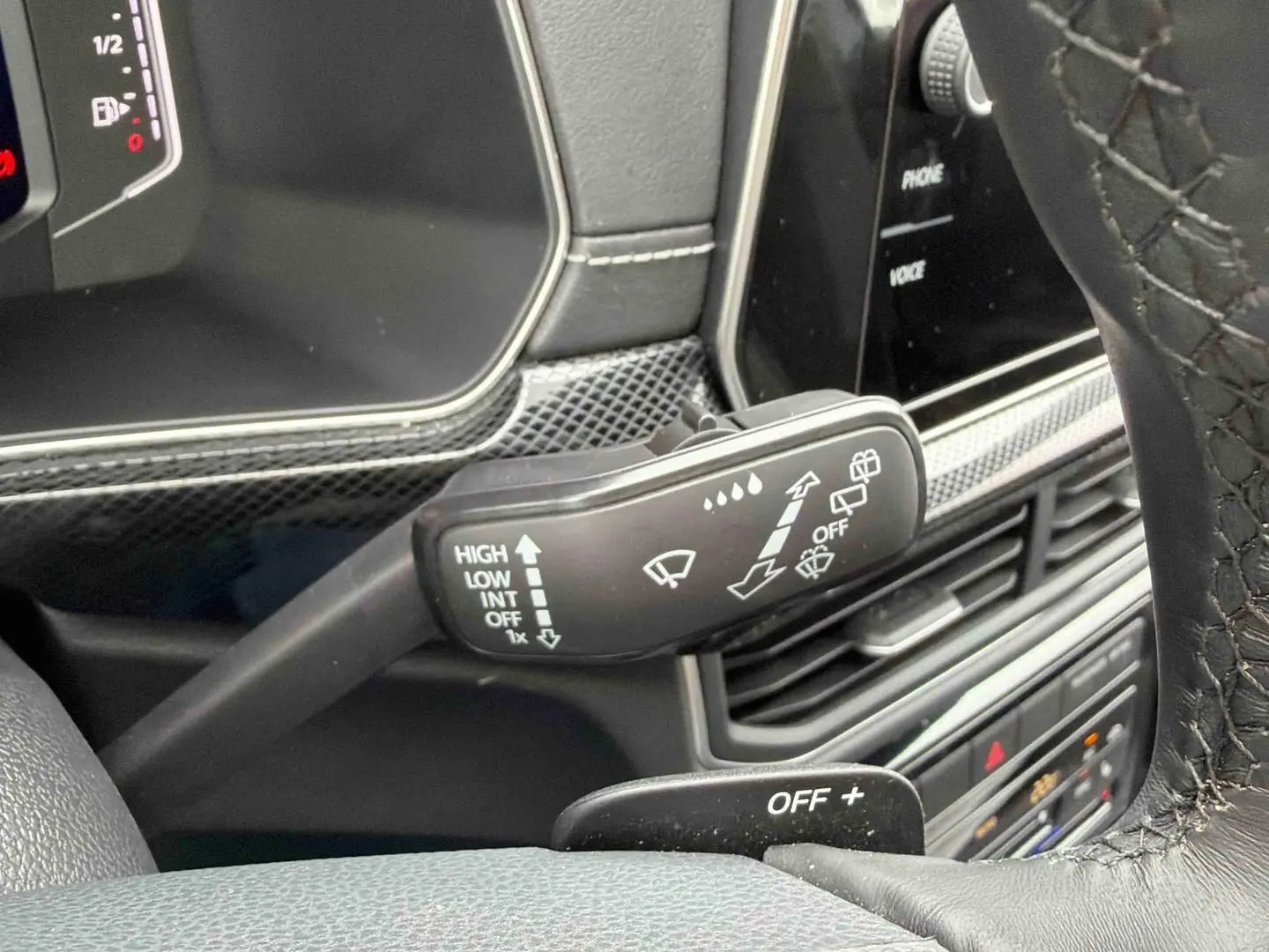 Gros plan sur la commande d’essuie-glace à gauche du volant du Volkswagen T-Cross gris, intérieur noir.