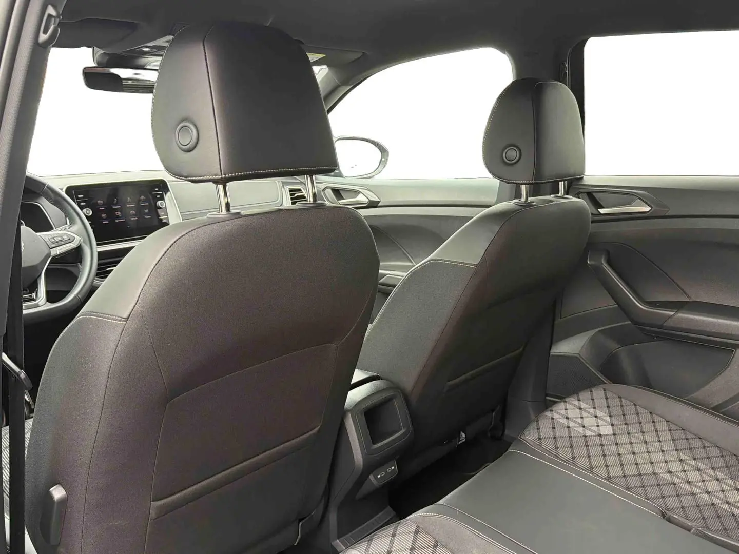 Vue intérieure arrière du Volkswagen T-Cross 2025 montrant les sièges avant noirs et la banquette arrière avec tissu à motif.