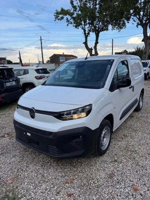 Vue 3/4 avant droite d'un Citroën Berlingo blanc 2026 version Van M Diesel, avec calandre noire et phares allumés.