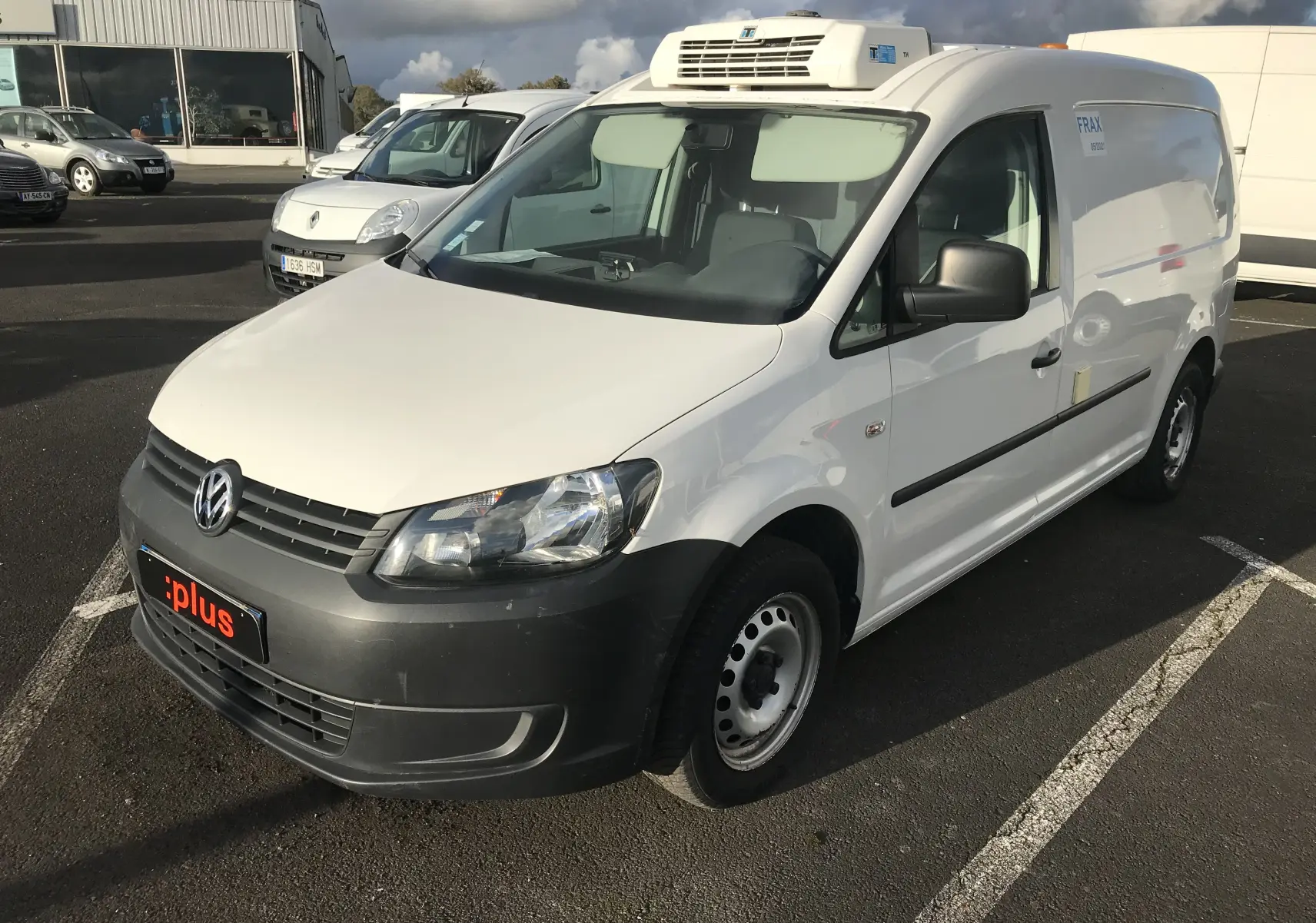 Vue 3/4 avant droit d'un utilitaire Volkswagen Caddy Maxi Van frigo blanc avec calandre noire et toit frigorifique.