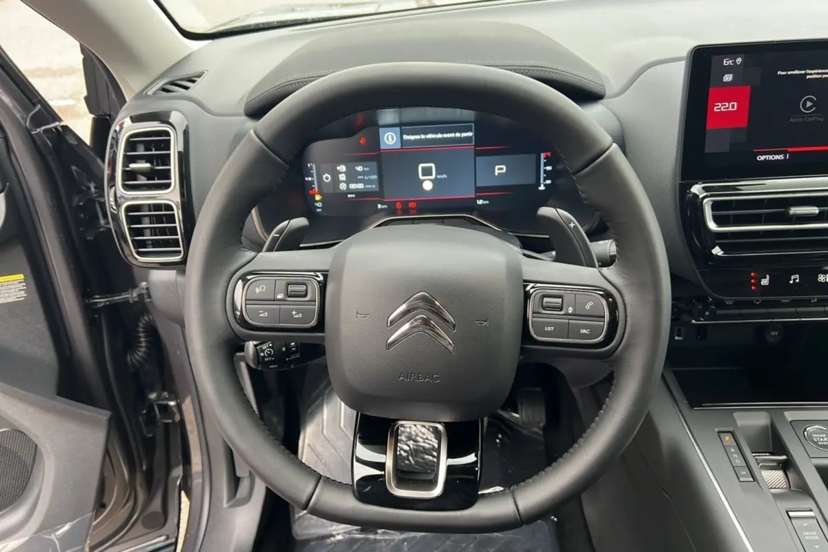 Vue centrée sur le volant et le tableau de bord numérique du Citroën C5 Aircross 2025 gris platinium avec toit noir.