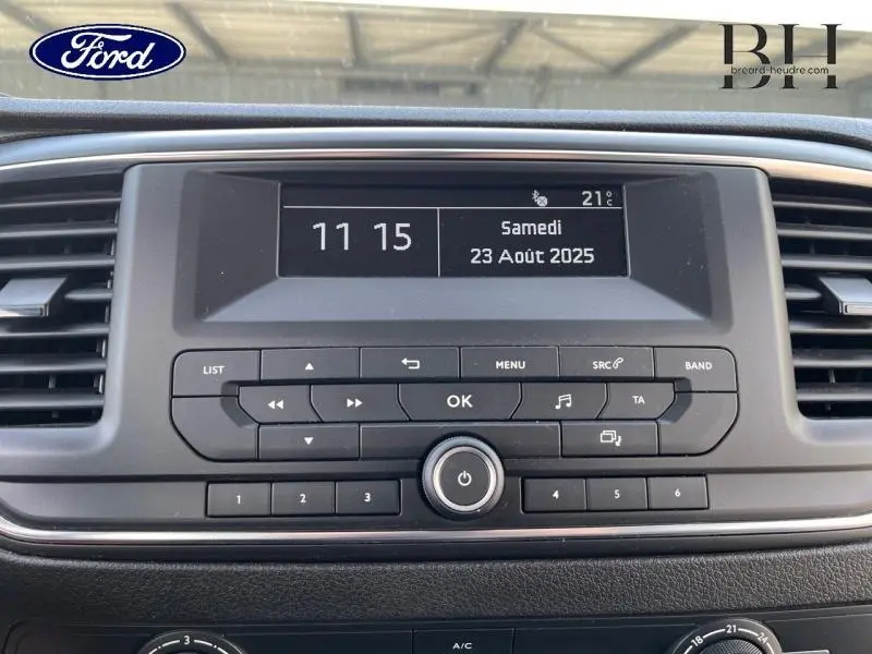 Tableau de bord central d'un Peugeot Expert Fourgon blanc, affichage digital avec horloge et commandes radio visibles.