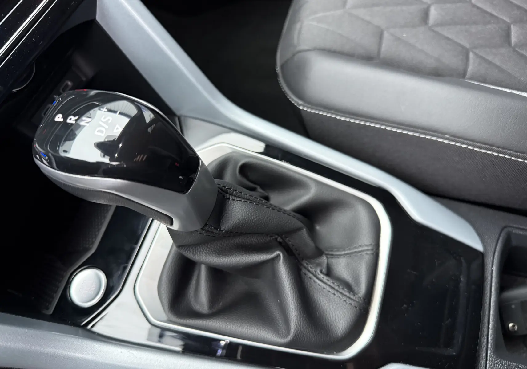 Vue rapprochée du levier de vitesse automatique noir et argenté du Volkswagen T-Roc 2025, avec sellerie grise visible.
