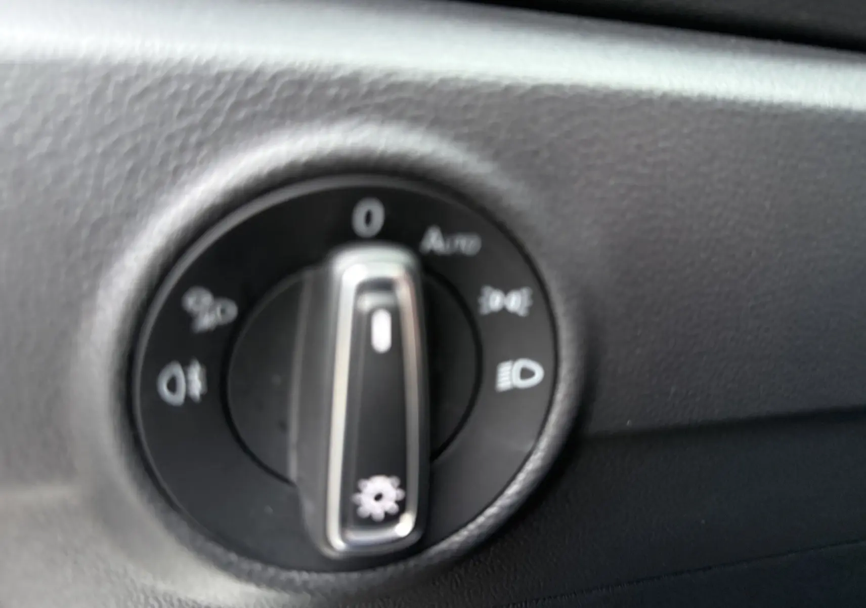 Gros plan sur le bouton de commande des phares dans l’habitacle du Volkswagen T-Roc blanc toit noir.