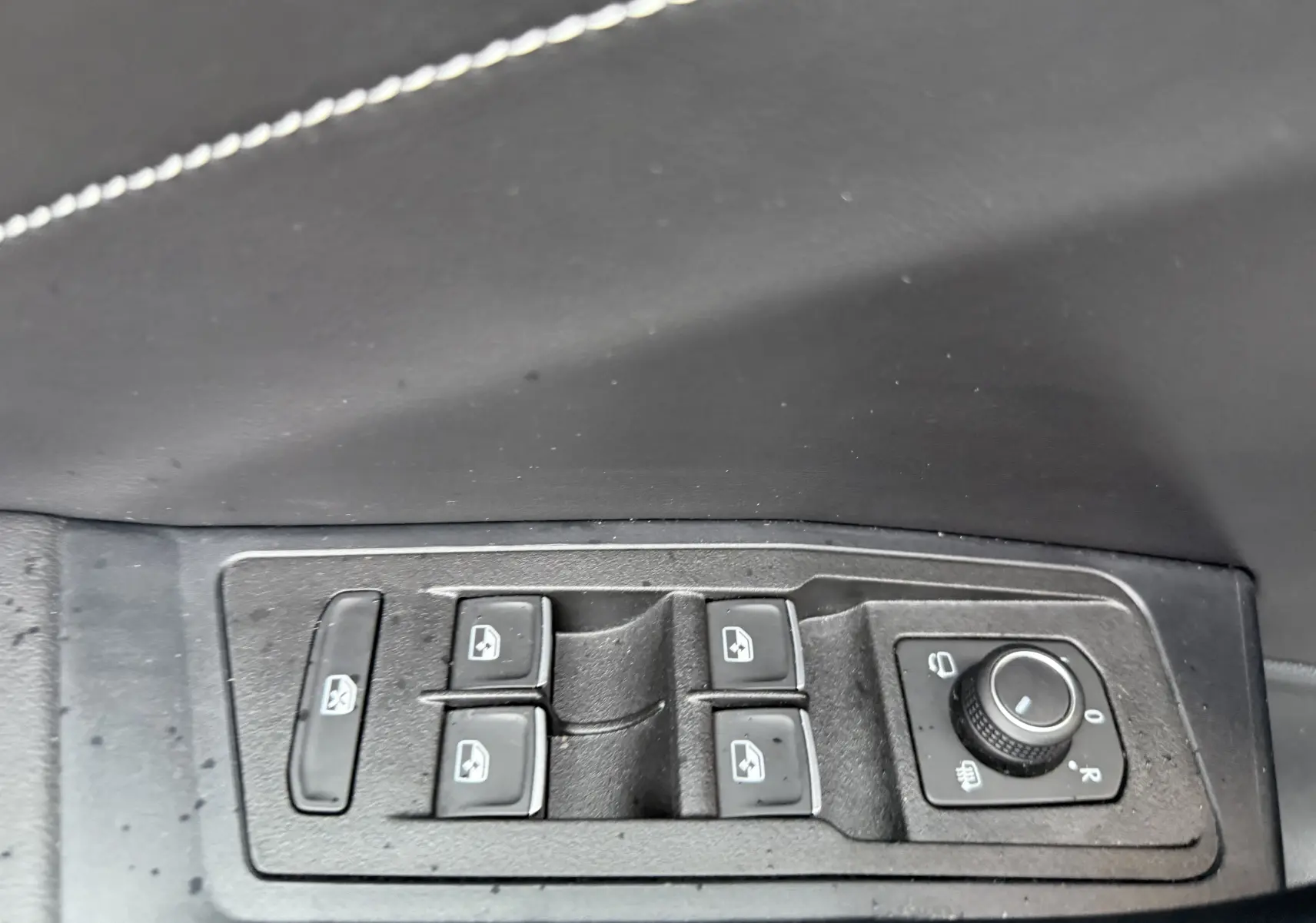 Gros plan sur les commandes des vitres et rétroviseurs côté gauche d’un Volkswagen T-Roc blanc toit noir 2025.