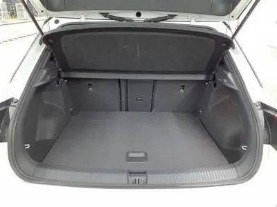 Coffre ouvert du Volkswagen T-Roc blanc pure toit noir, vue arrière montrant un espace de chargement spacieux et propre.