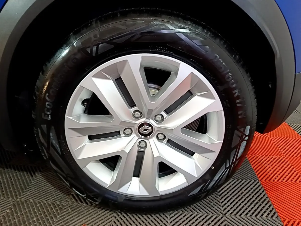 Gros plan sur la jante alliage argentée du Renault Captur bleu, mettant en valeur le logo central Renault.