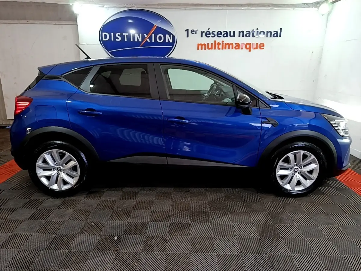 Profil droit d’un Renault Captur bleu 2023 avec jantes alliage et rétroviseurs noirs dans un showroom.