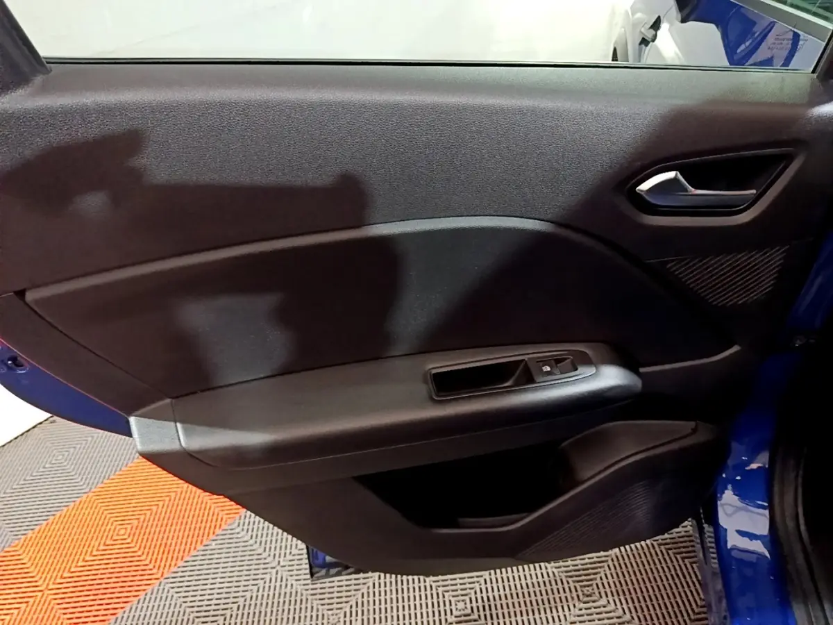 Vue intérieure de la porte arrière droite du Renault Captur bleu 2023, avec poignée et commande de fenêtre noire.