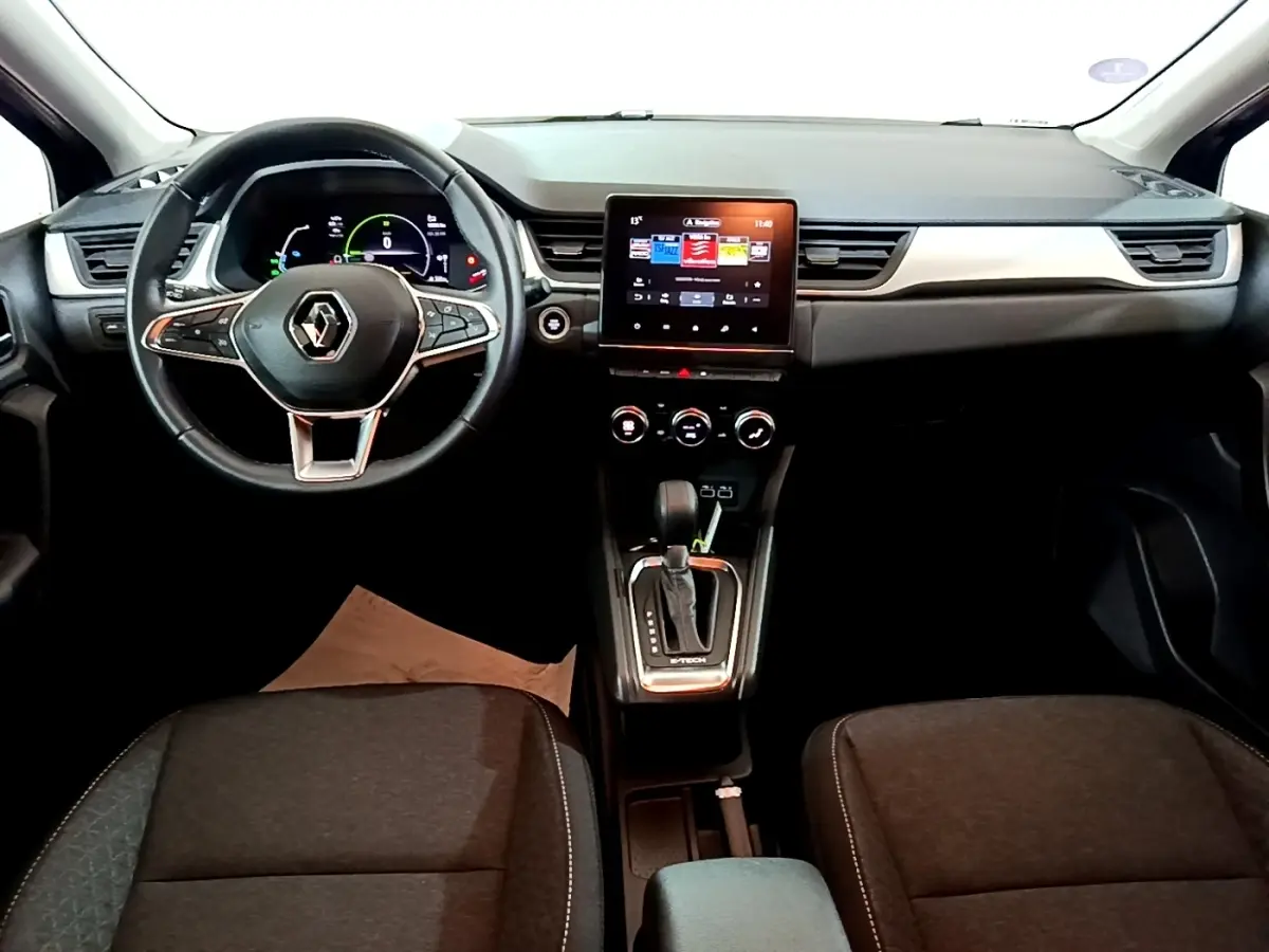 Vue intérieure avant du Renault Captur bleu, tableau de bord moderne avec écran tactile central et volant multifonctions.