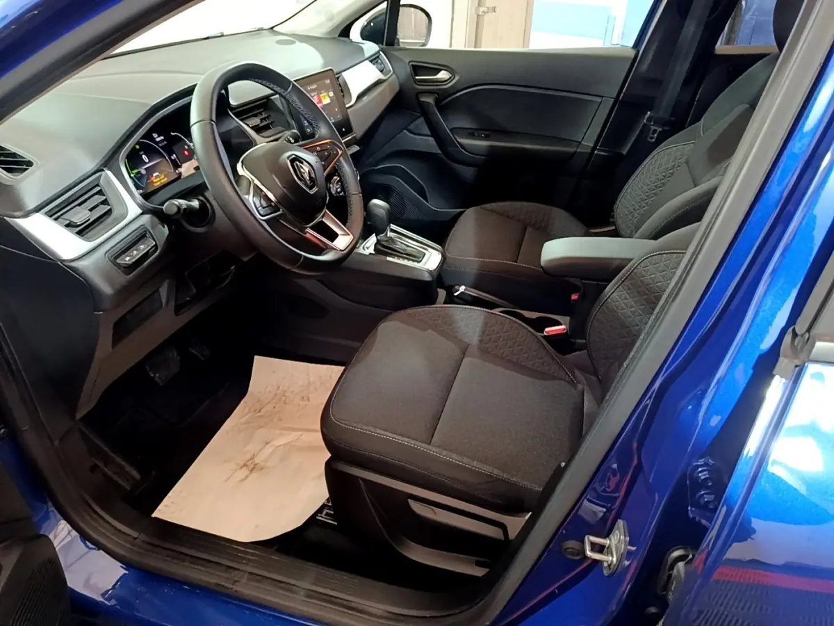 Vue intérieure côté conducteur du Renault Captur bleu 2023, avec volant multifonctions et sièges noirs tissu.