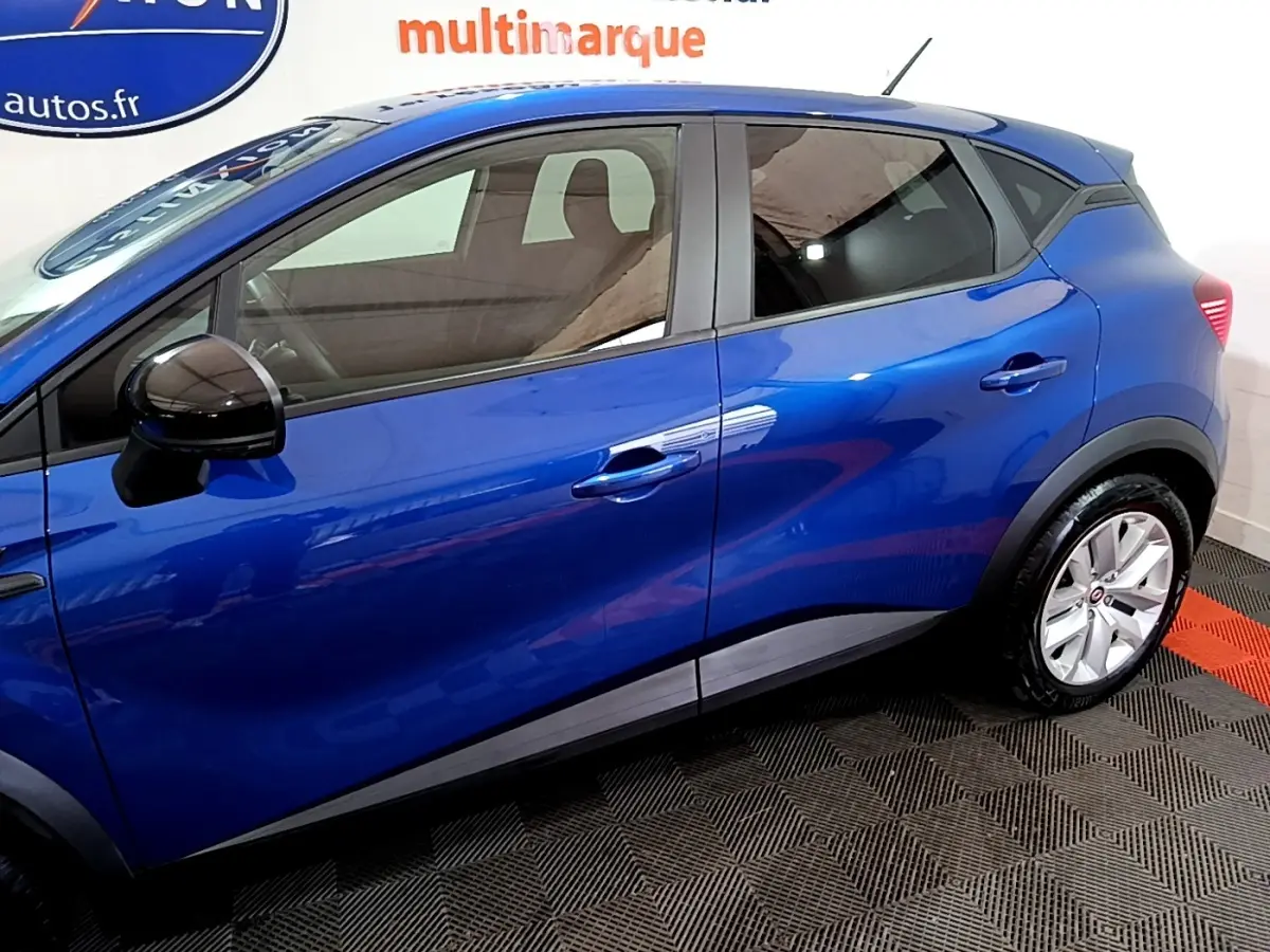 Vue latérale côté gauche du Renault Captur bleu 2023 avec rétroviseur noir et jantes argentées.
