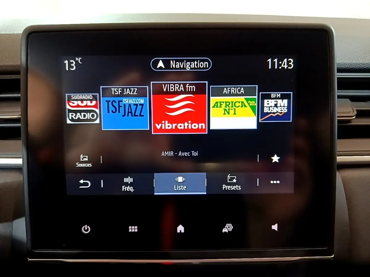 Écran tactile central du tableau de bord du Renault Captur bleu, affichant les stations radio et la navigation.