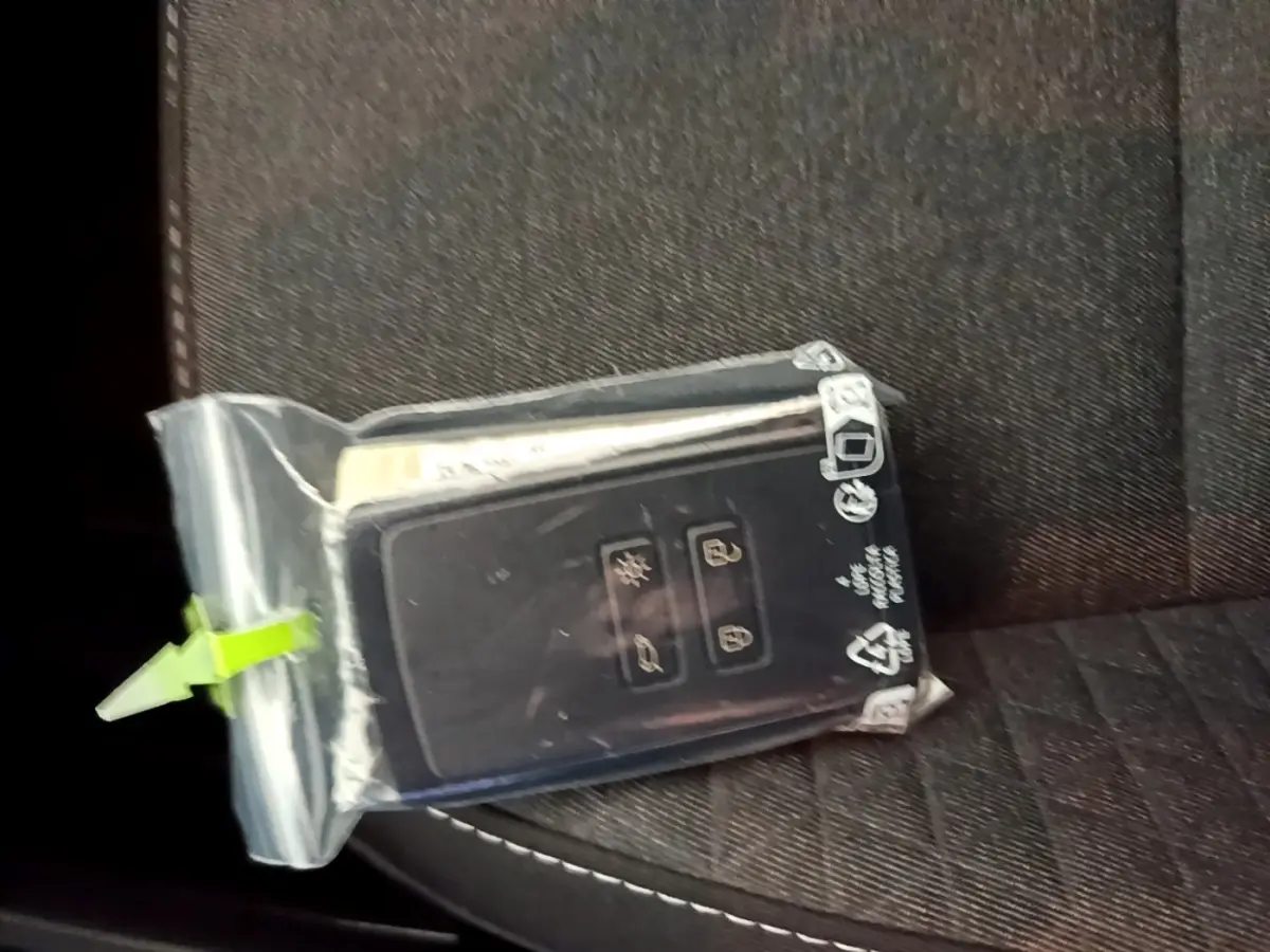 Clé Renault Captur bleu dans un sachet plastique posée sur un siège tissu noir à surpiqûres blanches.