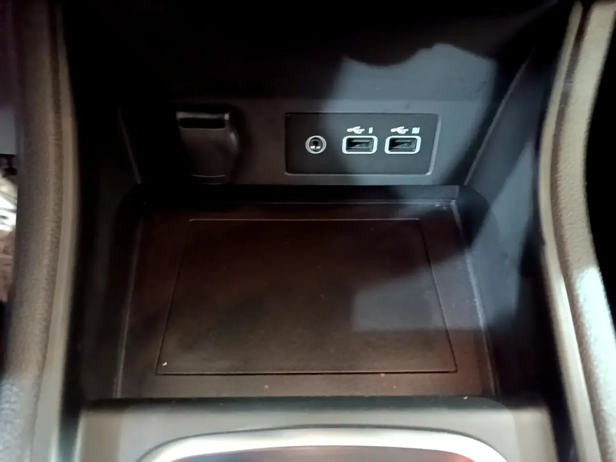 Gros plan sur la console centrale noire du Renault Captur bleu 2023, montrant deux ports USB et une prise jack.