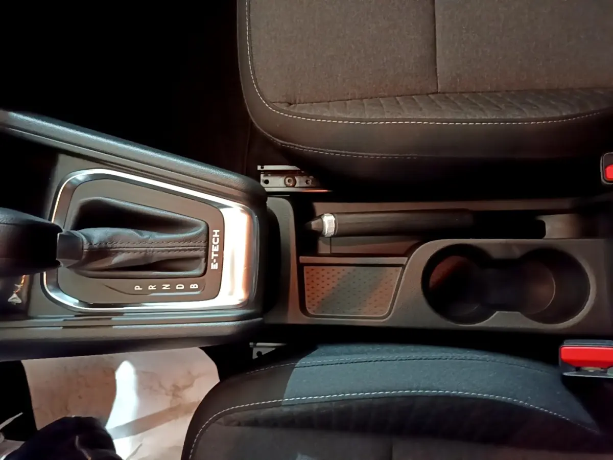 Vue plongeante sur la console centrale noire du Renault Captur E-Tech avec levier de vitesses automatique et frein à main manuel.