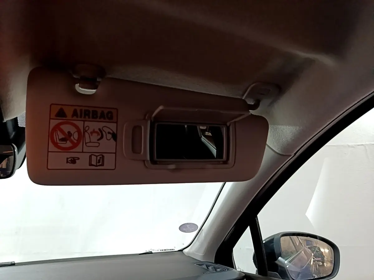 Détail intérieur sur le pare-soleil côté conducteur avec miroir et avertissement airbag dans un Renault Captur bleu 2023.