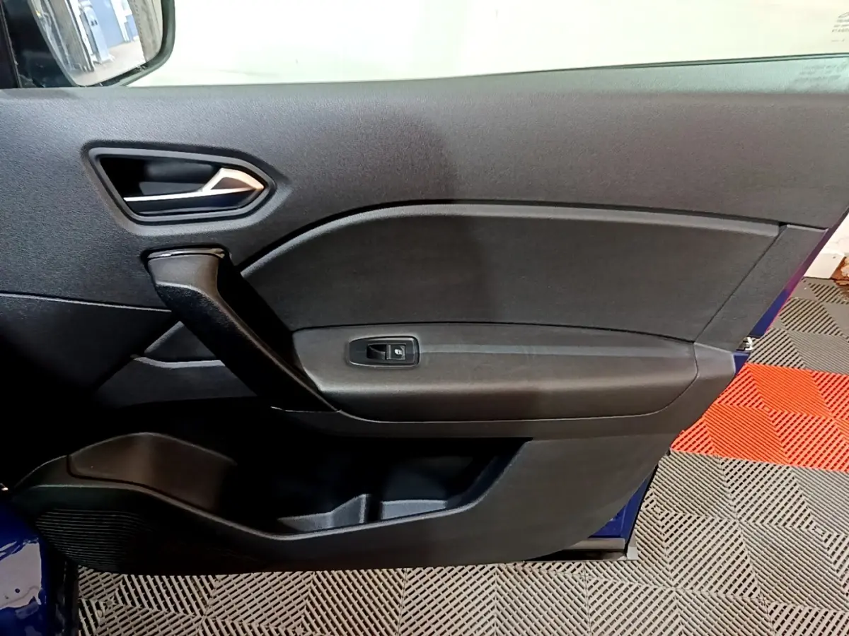 Vue intérieure du panneau de porte côté conducteur du Renault Captur bleu 2023, avec poignée noire et commande de vitre.
