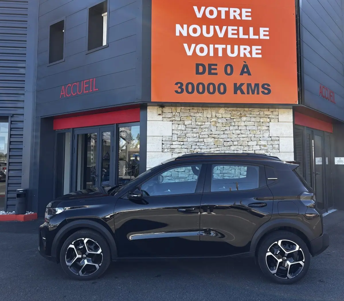 Vue de profil côté gauche d'une Citroën C3 noire 2025 avec jantes 16 pouces, stationnée devant un bâtiment commercial.