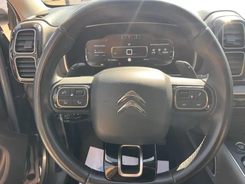 Vue rapprochée du volant cuir multifonction noir du Citroën C5 Aircross avec tableau de bord numérique en arrière-plan.