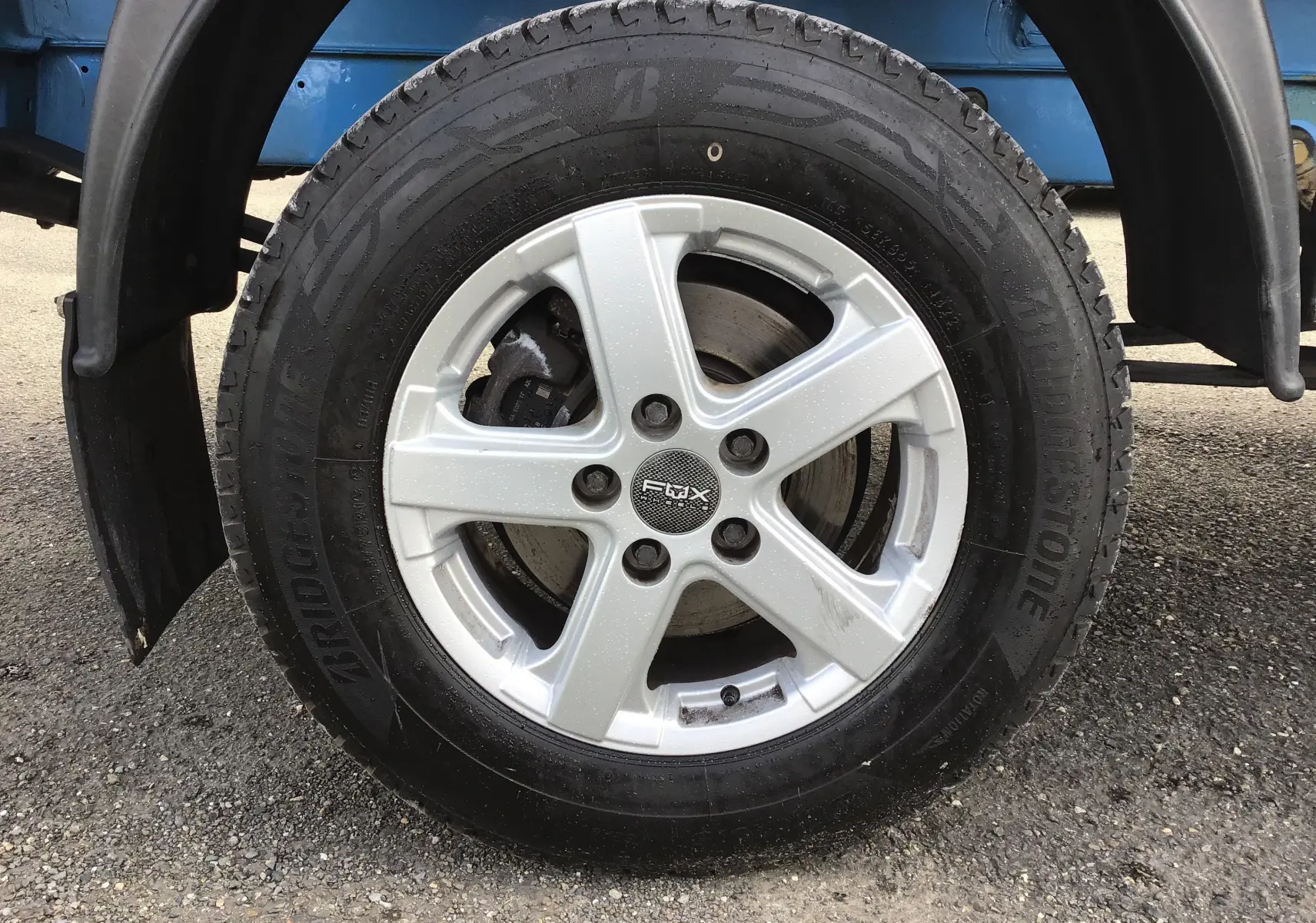 Gros plan sur la roue avant gauche du Volkswagen Crafter bleu, jante alliage cinq branches et pneu Bridgestone.