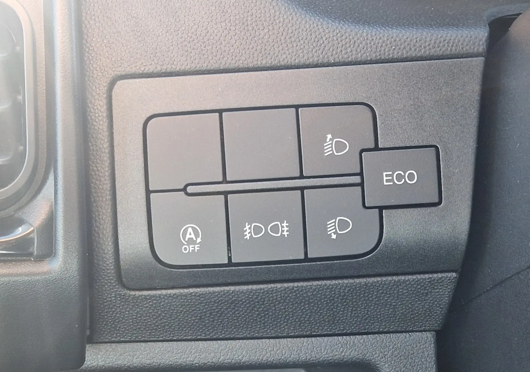 Gros plan sur les boutons de commande d'éclairage et mode ECO dans l'habitacle du Fiat Ducato Chassis Benne blanc 2023.