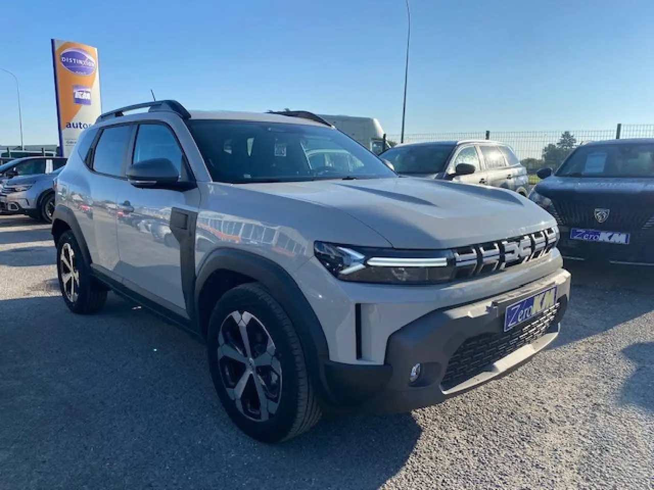SUV Dacia Duster 2025 beige Sandstone vu en 3/4 avant droit avec calandre distinctive et jantes noires.