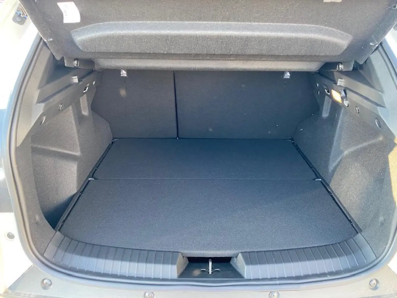 Coffre ouvert du Dacia Duster beige Sandstone 2025, vue intérieure montrant un espace de chargement spacieux et propre.