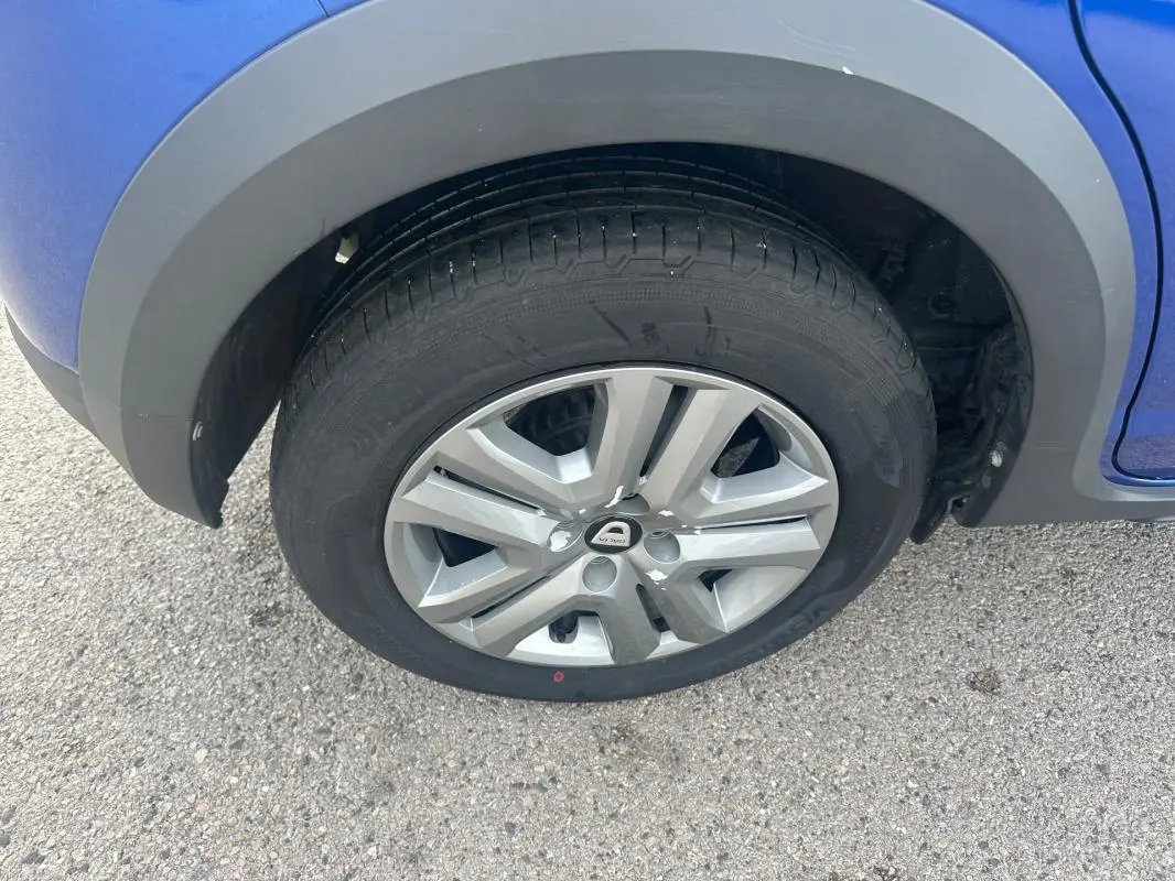 Gros plan sur la roue avant droite d'une Dacia Sandero Stepway bleu foncé avec jante alliage et passage de roue noir.