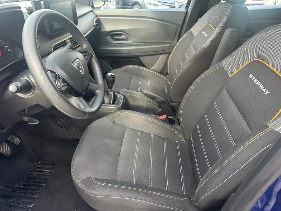 Vue intérieure côté conducteur de la Dacia Sandero Stepway 2021 avec sièges noirs marqués Stepway et volant réglable.