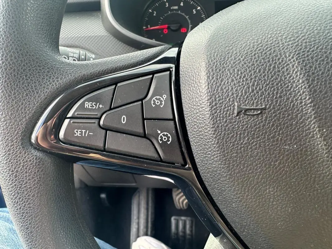 Gros plan sur les commandes du régulateur de vitesse à gauche du volant en cuir d'une Dacia Sandero Stepway bleu foncé 2021.
